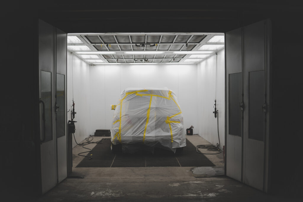 vehicle covered with a white sheet and yellow tape in a car service garage